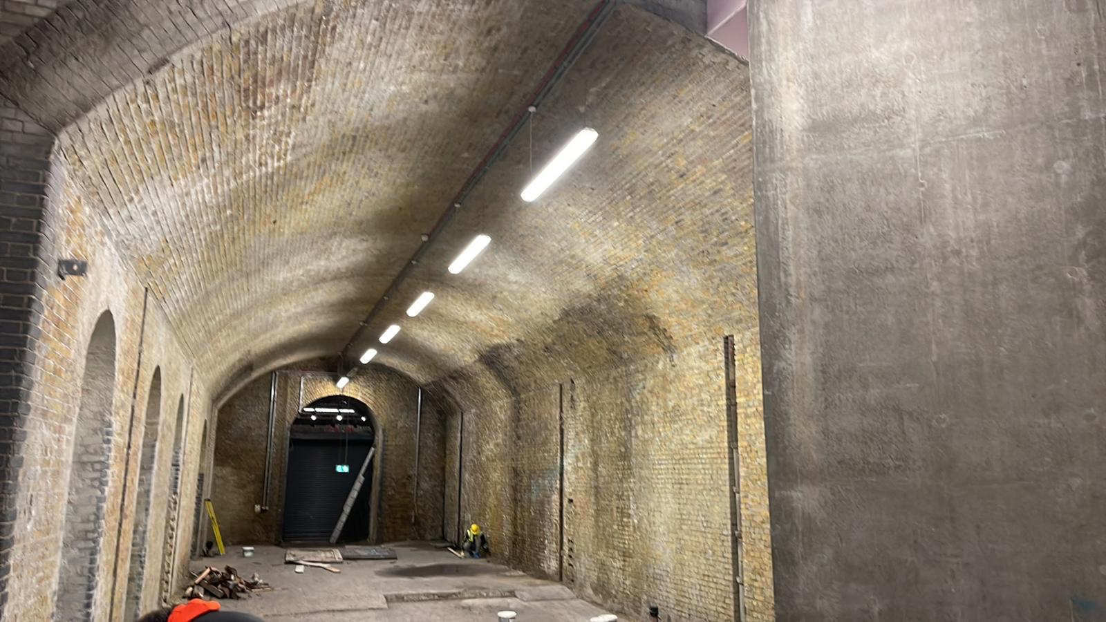 Stripped-back railway arch with exposed brick vault during commercial fit-out