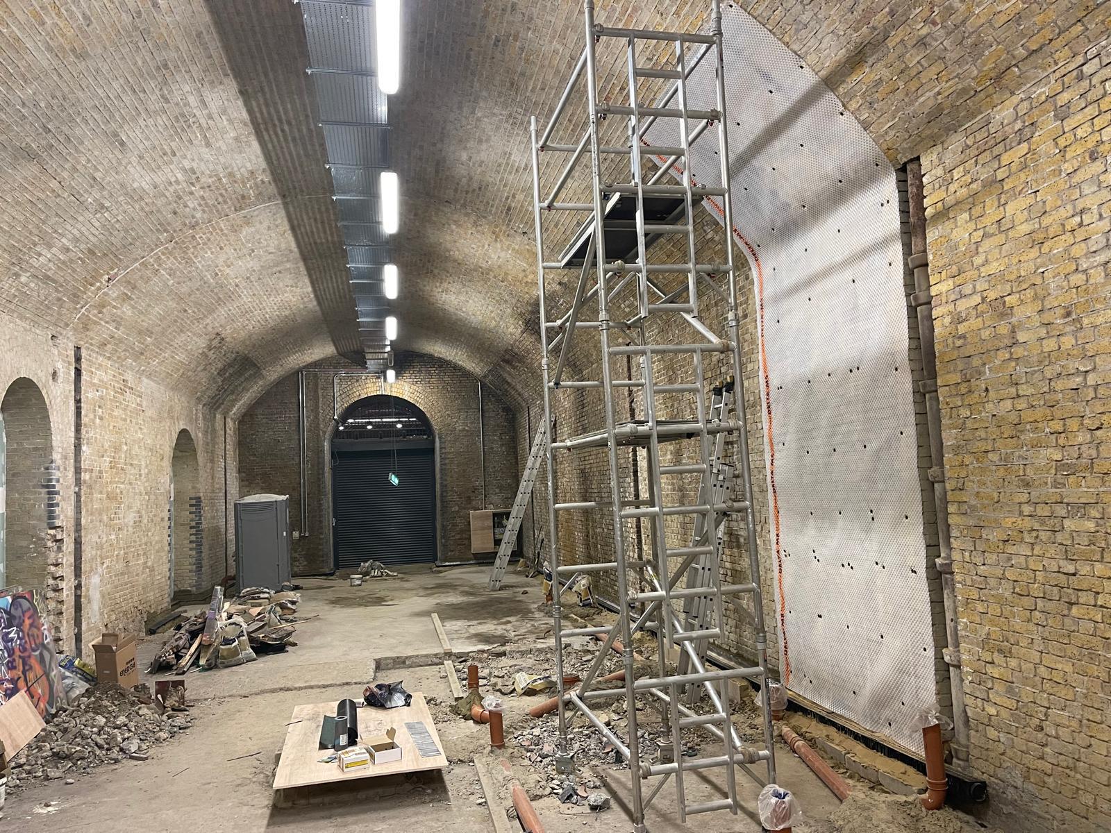 Mid-works commercial fit-out with scaffold tower and tanking membrane on arch wall