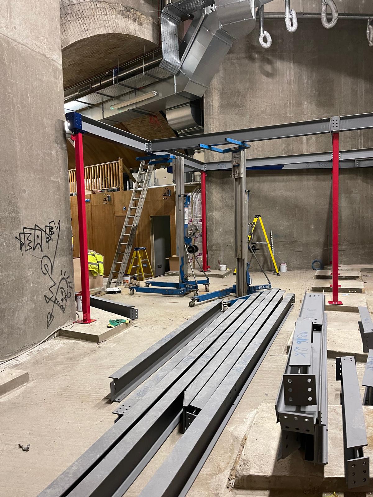 New structural steelwork installed in commercial arch with red props and grey beams