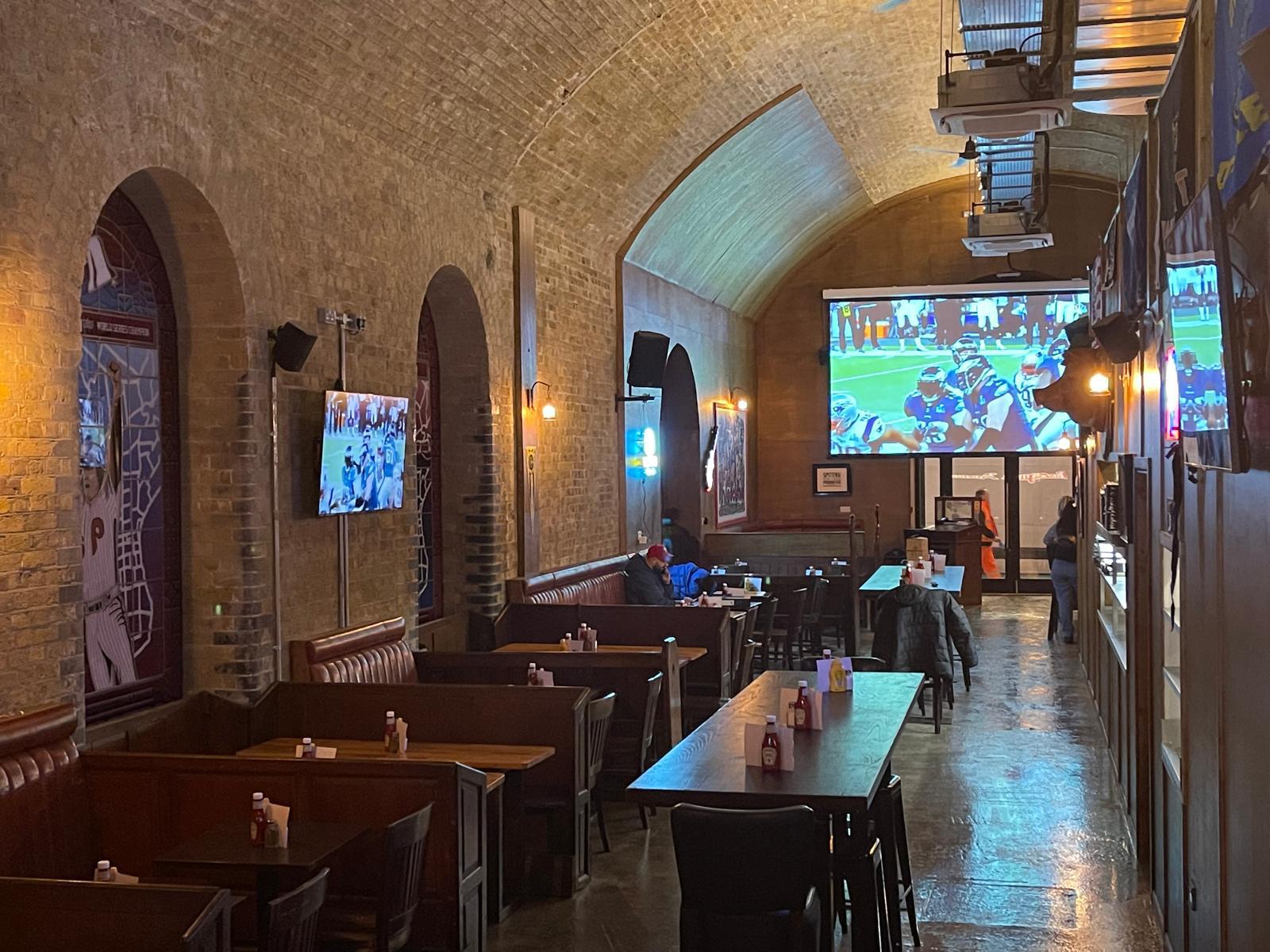Completed sports bar fit-out under brick vaulted ceiling with booth seating and big screens