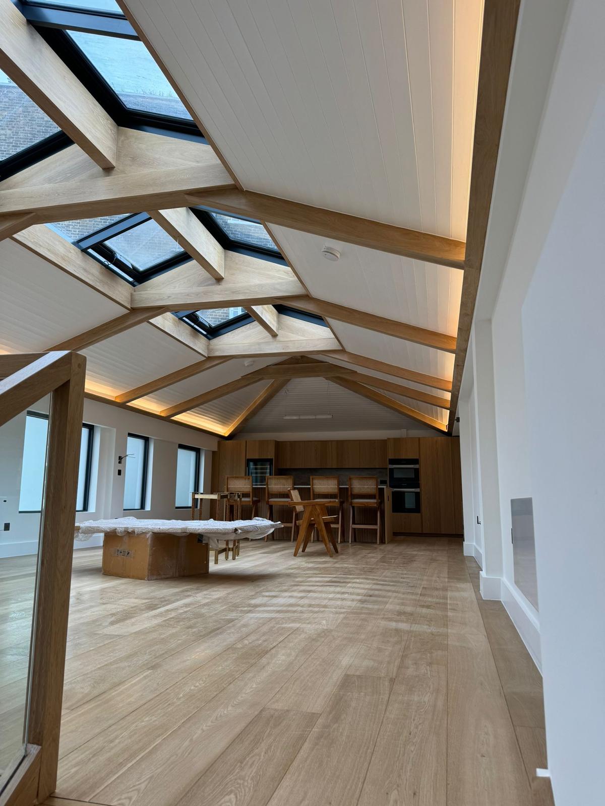 Open-plan loft interior with vaulted oak beam ceiling and skylights