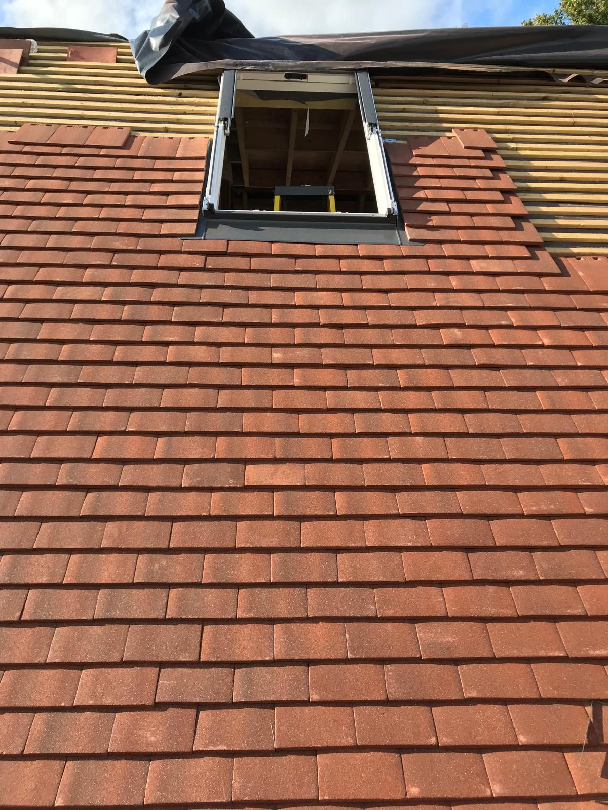 New roof tiles being laid around a Velux window during a loft conversion