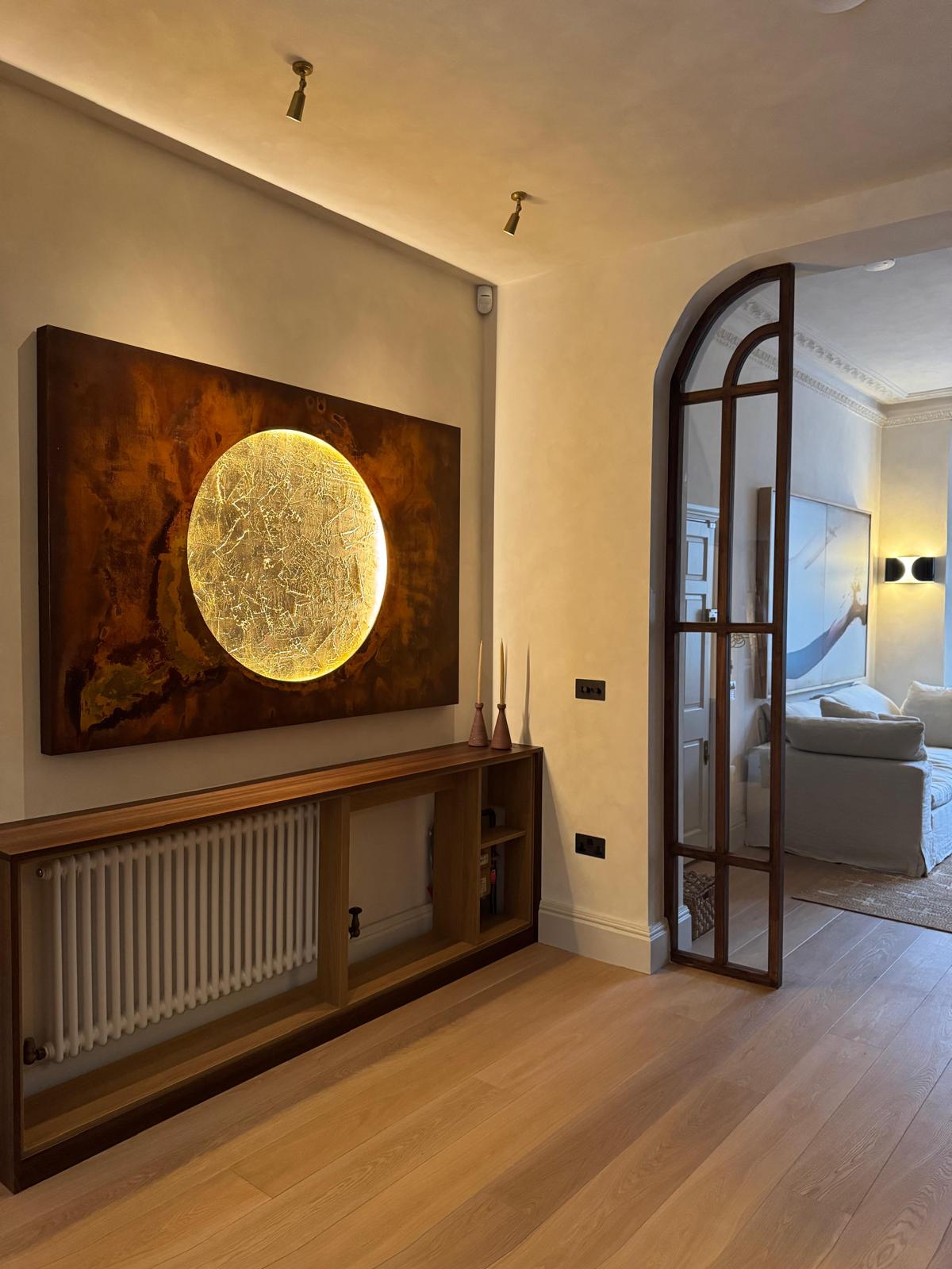 Reception room with bespoke walnut media unit, illuminated artwork and arched glass door