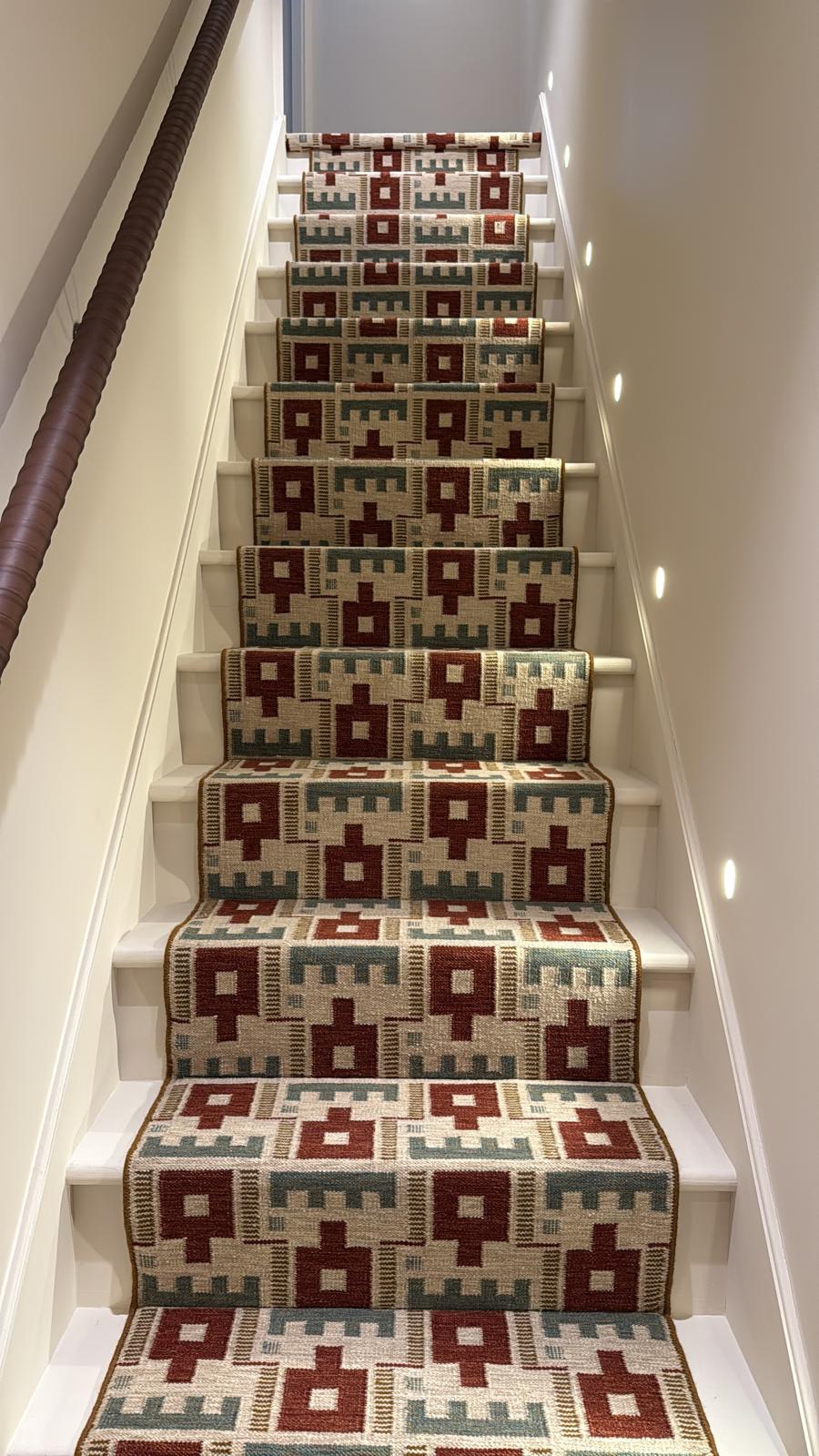 Refurbished staircase with patterned kilim runner and recessed wall lighting