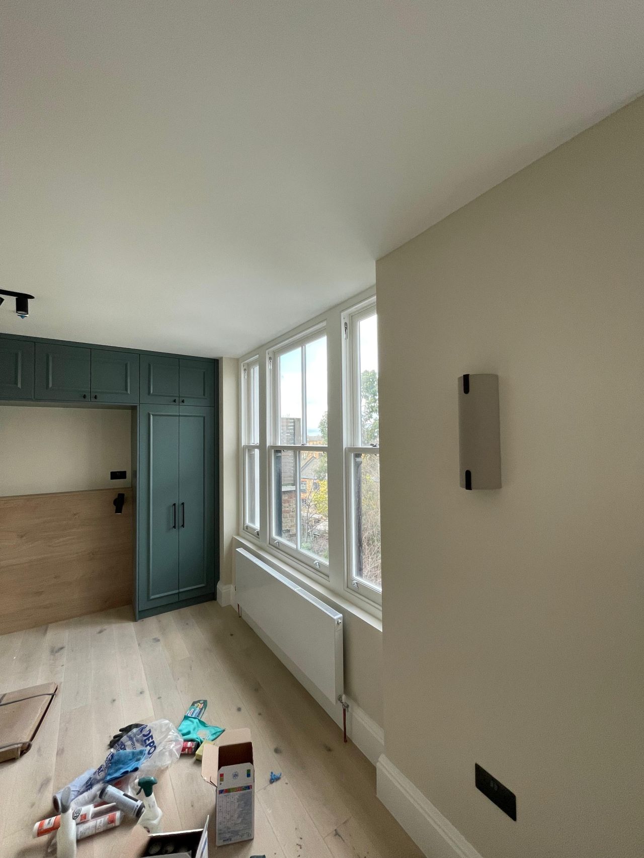 Bedroom refurbishment with green fitted joinery and large sash windows
