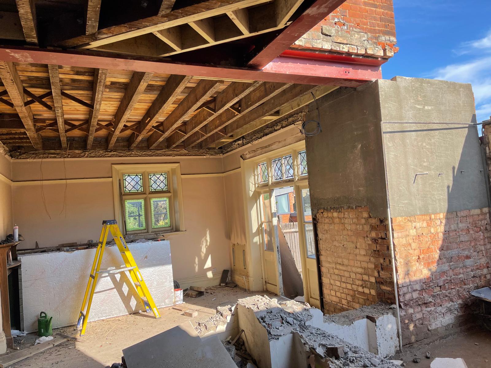 Structural strip-out with red RSJ steel beams supporting period roof and walls